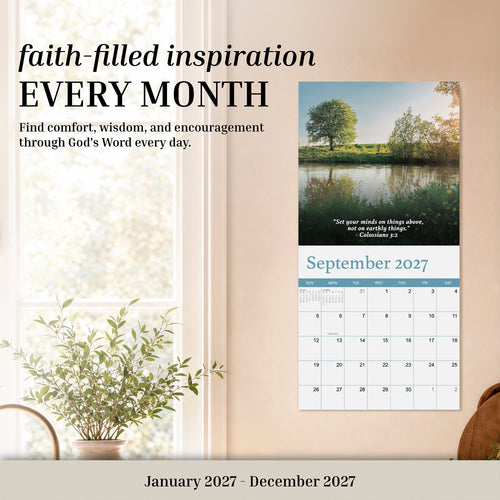 A 2027 Religious Wall Calendar from HannahFaithstore hangs open to September beside a leafy plant, featuring inspirational faith-based text above it—making this an ideal gift for anyone seeking spiritual encouragement.