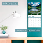 The HannahFaithstore 2026 Religious Wall Calendar, a 12-month faith-based calendar with inspiring Bible verses for each month (Jan-Dec), hangs above a desk with books, a potted plant, and a white lamp.